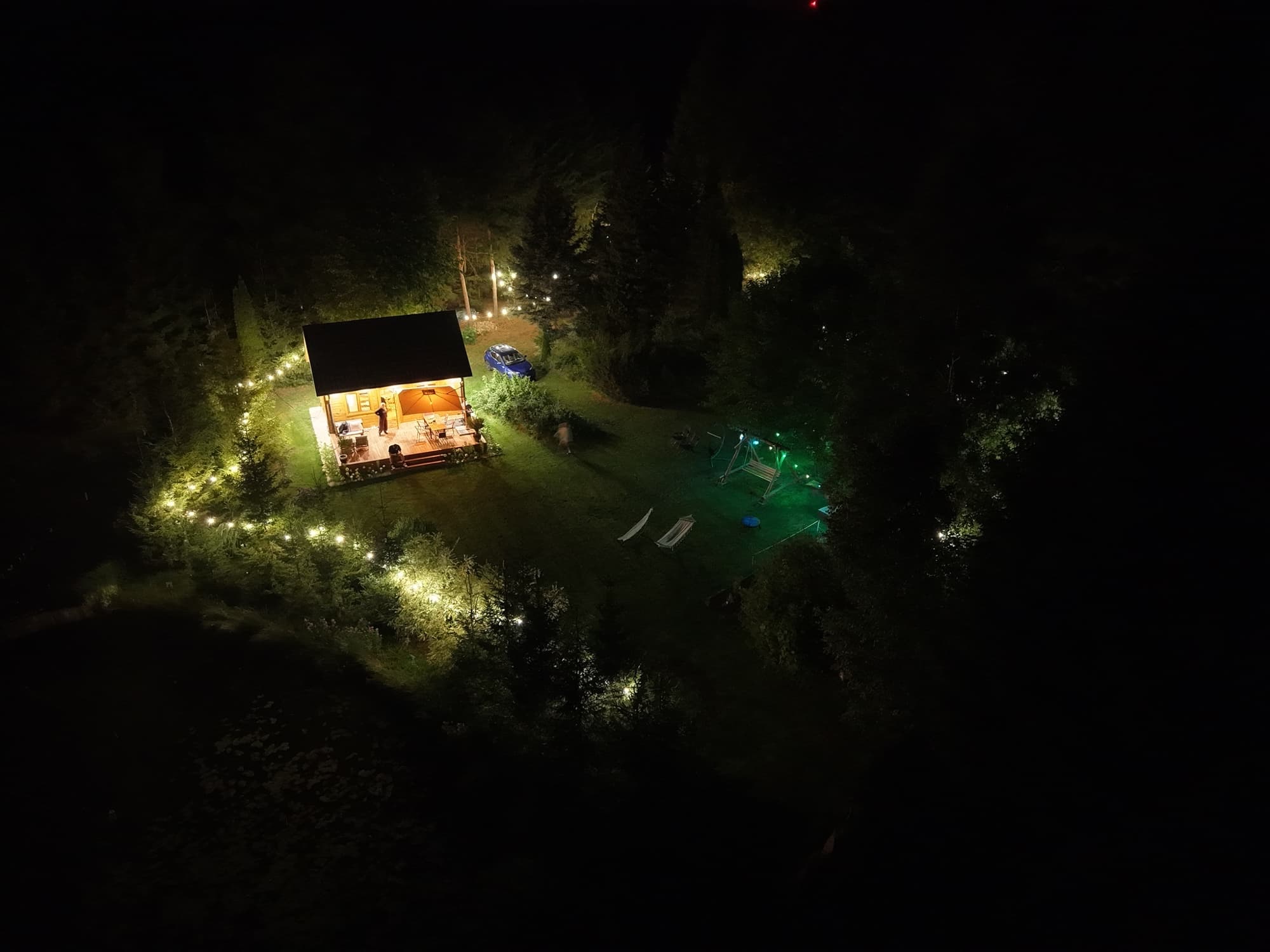 Domek nocą z drona — zielone jacuzzi i staw