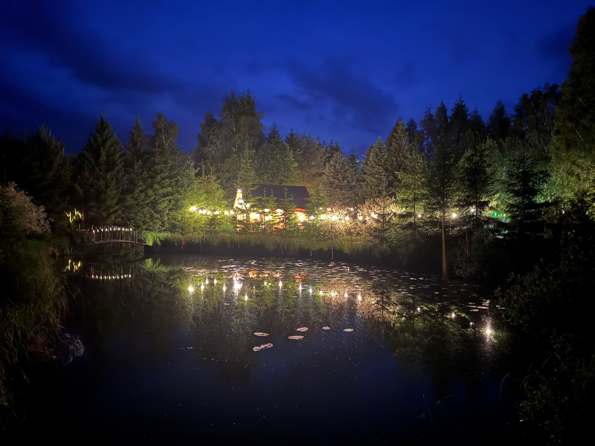 Domek i swiatla nocne odbite w szerokim stawie