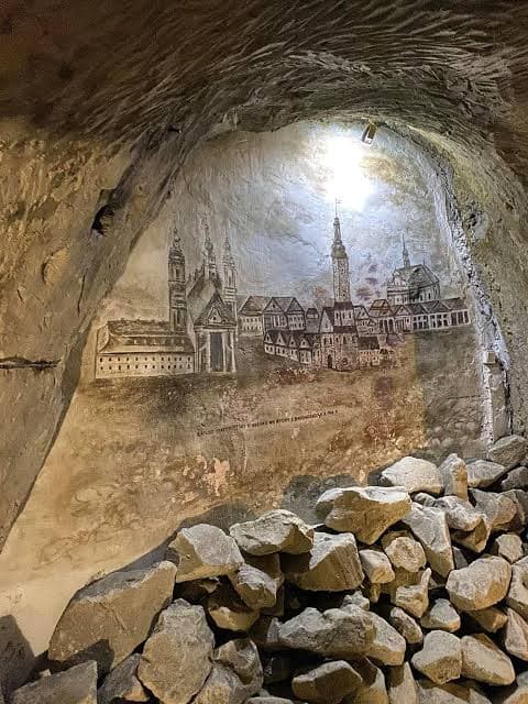 Podziemia Kredowe — widok na mural z panoramą Chełma przez skalne łuki